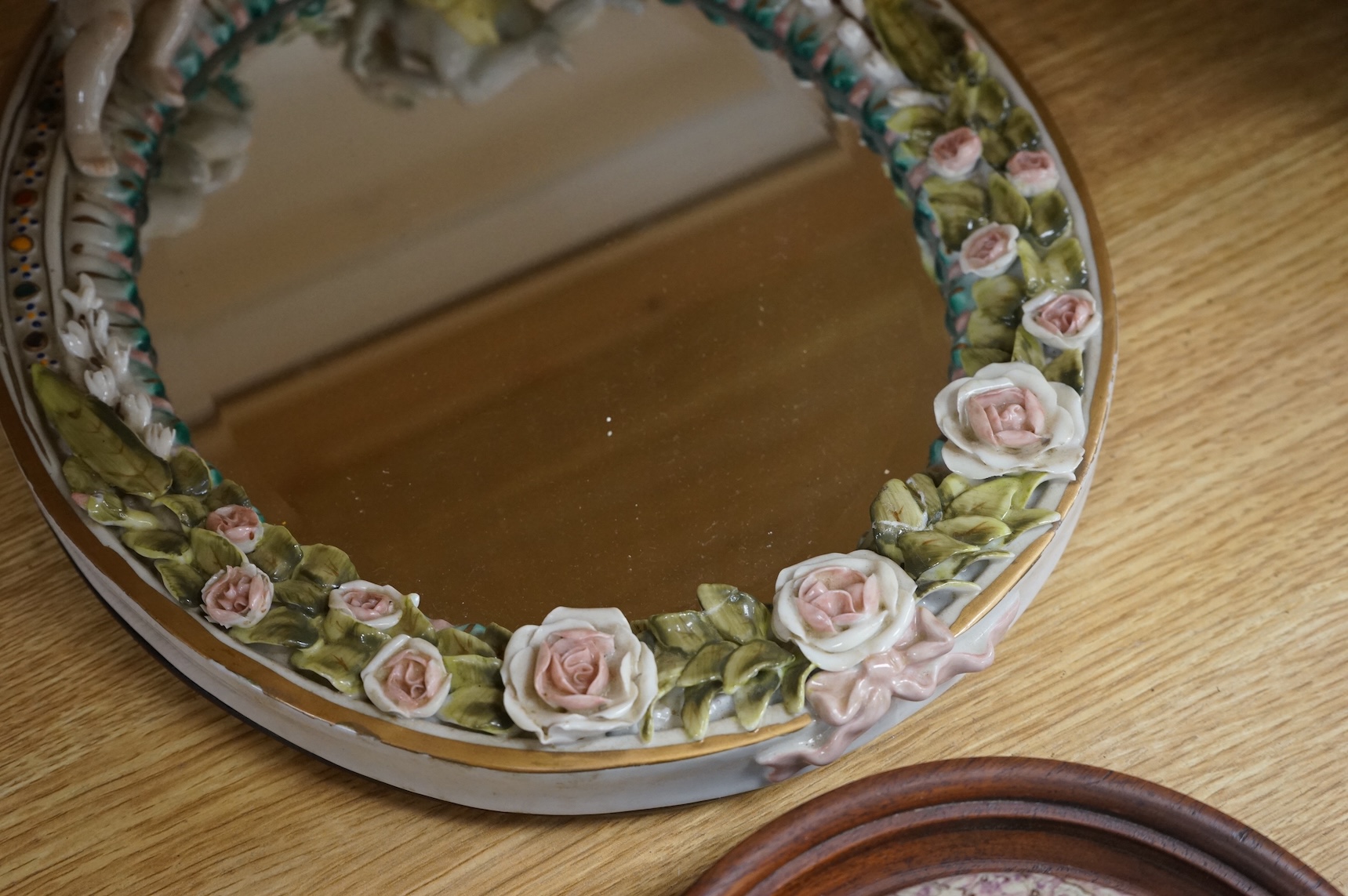 A Duke of Wellington pot lid, another Prattware pot lid and a German floral encrusted porcelain mirror, largest 33cm high